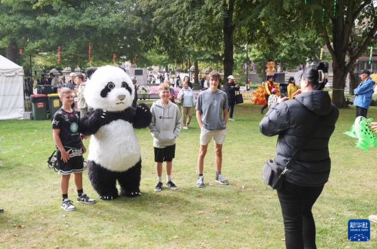 2月7日，游客在新西蘭克賴斯特徹奇新春嘉年華活動上與熊貓人偶合影。新華社記者 龍雷 攝