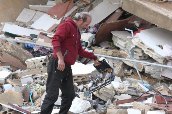 　2月21日，在黎巴嫩南部的邁斯杰貝勒，一名返回家園的男子查看廢墟中的物品。新華社發(fā)（塔希爾·阿布·哈姆丹攝）