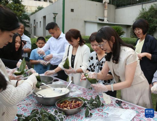 5月27日，在伊朗首都德黑蘭，人們在中國駐伊朗大使館舉行的“香囊飄香 端午安康”節(jié)日慶?；顒由象w驗包粽子。新華社記者 沙達提 攝