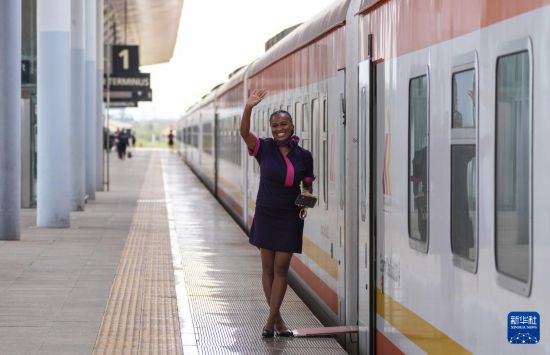 5月31日，在蒙內鐵路內羅畢站，一名乘務員在即將開往蒙巴薩的E2次列車旁等候乘客。新華社記者 李亞輝 攝