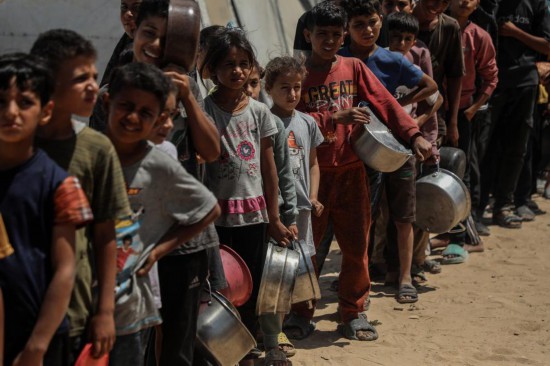 5月28日，孩子們?cè)诩由吵俏鞑康纳程犭y民營(yíng)等待領(lǐng)取救助食物。新華社發(fā)（里澤克·阿卜杜勒賈瓦德攝）