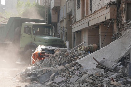  6月13日，在伊朗首都德黑蘭，救援人員清理在以軍襲擊中受損的建筑。新華社發(fā)