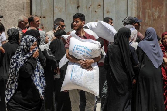 6月26日，巴勒斯坦人在加沙城領(lǐng)取援助物資。新華社發(fā)（里澤克·阿卜杜勒賈瓦德攝）