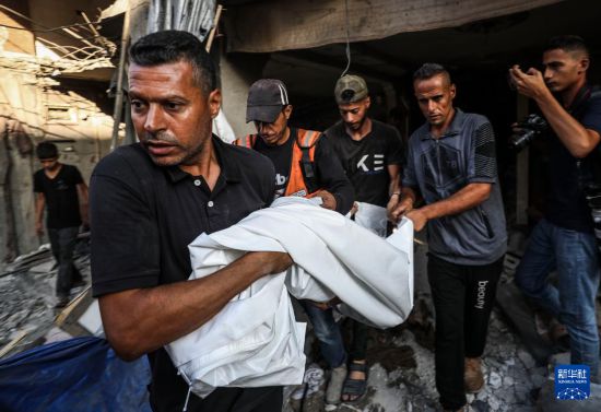 7月6日，巴勒斯坦人在加沙城搬運(yùn)遇難者遺體。新華社發(fā)（馬哈茂德·扎基攝）