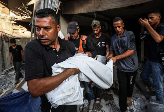 7月6日，巴勒斯坦人在加沙城搬運遇難者遺體。新華社發(fā)（馬哈茂德·扎基攝）