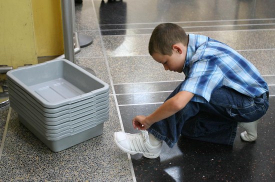 2006年8月10日，在美國首都華盛頓里根機(jī)場(chǎng)，一名小男孩在脫鞋準(zhǔn)備進(jìn)行安檢。 新華社記者呂明響攝