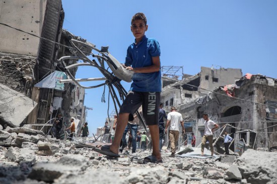 5月31日，在加沙城，一名青年在以軍襲擊后的廢墟中搜尋物品。新華社發(fā)（里澤克·阿卜杜勒賈瓦德攝）