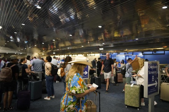 2024年7月19日，乘客在美國密爾沃基國際機(jī)場(chǎng)排隊(duì)辦理手續(xù)。新華社記者吳曉凌攝