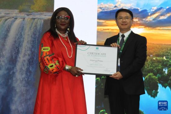 　　7月24日，在津巴布韋維多利亞瀑布城開幕的《濕地公約》第十五屆締約方大會(huì)上，《濕地公約》秘書長(zhǎng)穆松達(dá)·蒙巴為中國浙江杭州代表頒發(fā)“國際濕地城市”證書。新華社發(fā)（塔法拉攝）
