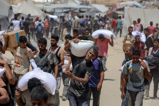 8月1日，在加沙地帶拜特拉希耶，人們搬運(yùn)援助物資。新華社發(fā)（里澤克·阿卜杜勒賈瓦德攝）