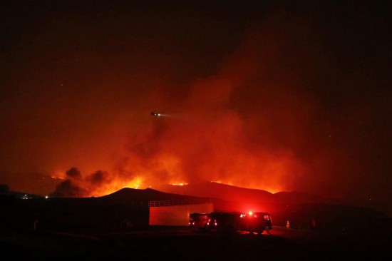 1月22日，在美國(guó)加利福尼亞州洛杉磯縣卡斯泰克市的一座山丘上，消防員與名為“休斯”的山火奮力搏斗。新華社發(fā)（邱晨攝）