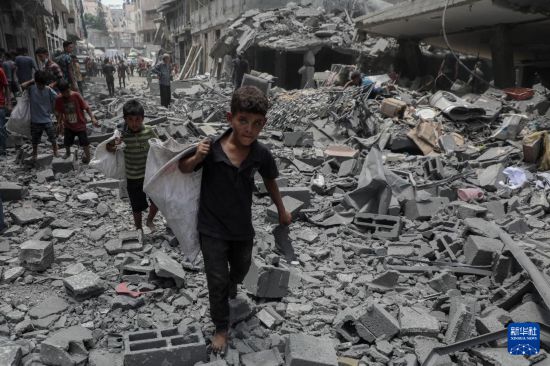  8月8日，孩子們?cè)诩由吵且攒娨u擊后的廢墟上搬運(yùn)物品。新華社發(fā)（里澤克·阿卜杜勒賈瓦德攝）