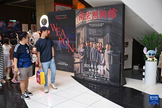 　8月24日，在馬來(lái)西亞吉隆坡，民眾觀看《南京照相館》電影海報(bào)。新華社記者 程一恒 攝