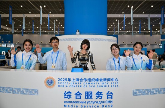 8月28日，可進行中、俄、英語互動的人形機器人“小合”與志愿者服務人員在綜合服務臺歡迎到訪記者。新華社記者 孫凡越 攝