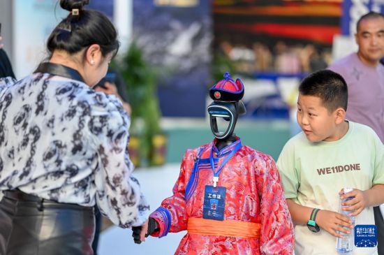 8月29日，觀眾在第五屆中蒙博覽會(huì)內(nèi)蒙古展區(qū)和機(jī)器人工作人員握手。新華社記者 連振 攝