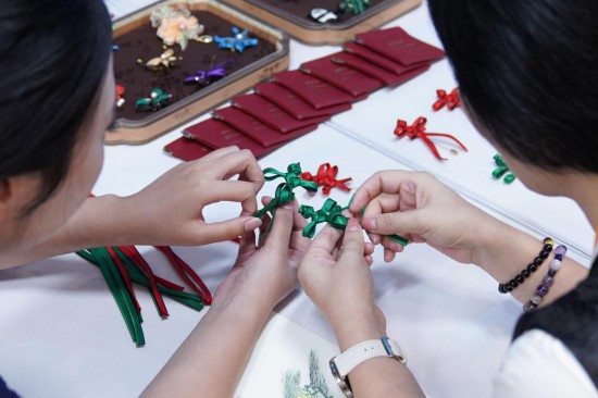 參會記者在2025年上海合作組織峰會新聞中心的曾氏華服傳統(tǒng)手工精細制作技藝展臺制作盤扣胸針。新華社記者戴明軒攝