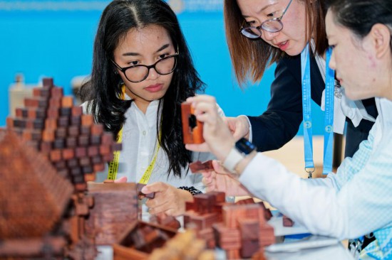 一名印度尼西亞記者（左）在2025年上海合作組織峰會新聞中心了解傳統(tǒng)木工榫卯技藝。新華社記者張笑宇攝