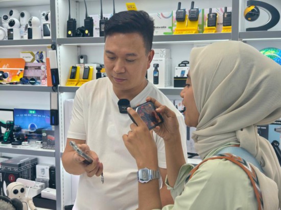 9月26日，在浙江金華義烏國際商貿(mào)城，印度尼西亞拉賈瓦里電視臺的新聞記者奧利維婭·費拉里（右）使用AI翻譯機與中國老板李軍交流。新華社記者 劉梓漪 攝