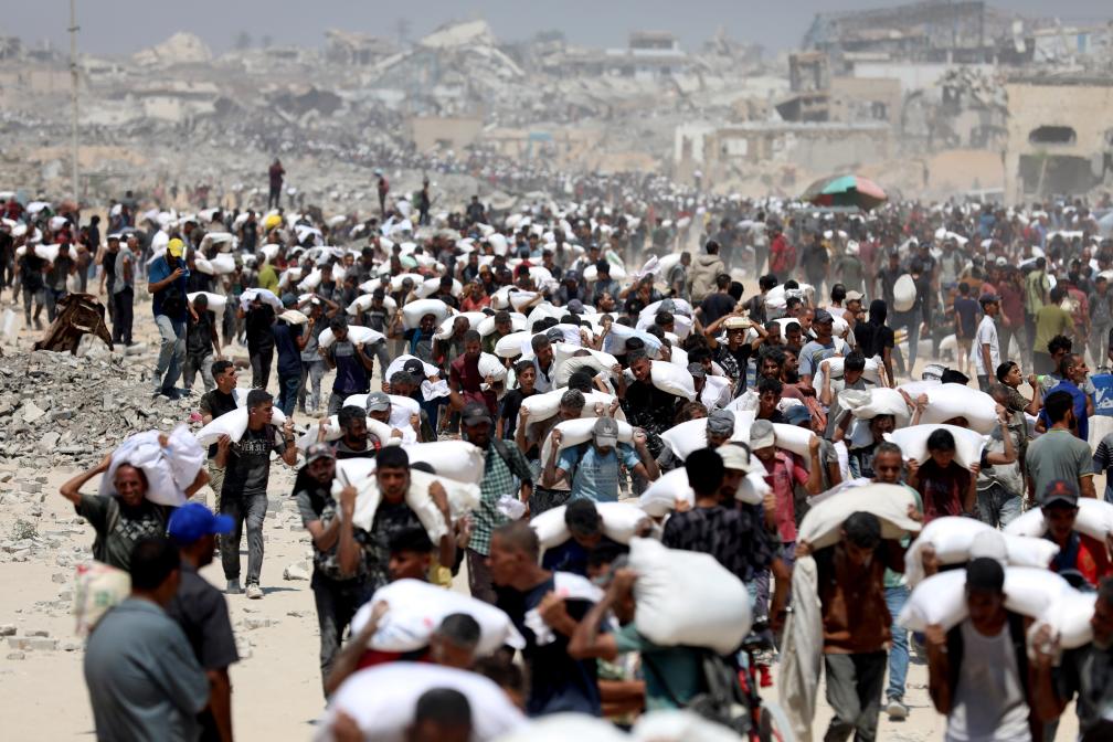 7月27日，在加沙地帶北部城鎮(zhèn)拜特拉希亞，人們領(lǐng)取通過邊境口岸進(jìn)入加沙的援助物資。新華社發(fā)（里澤克·阿卜杜勒賈瓦德攝）