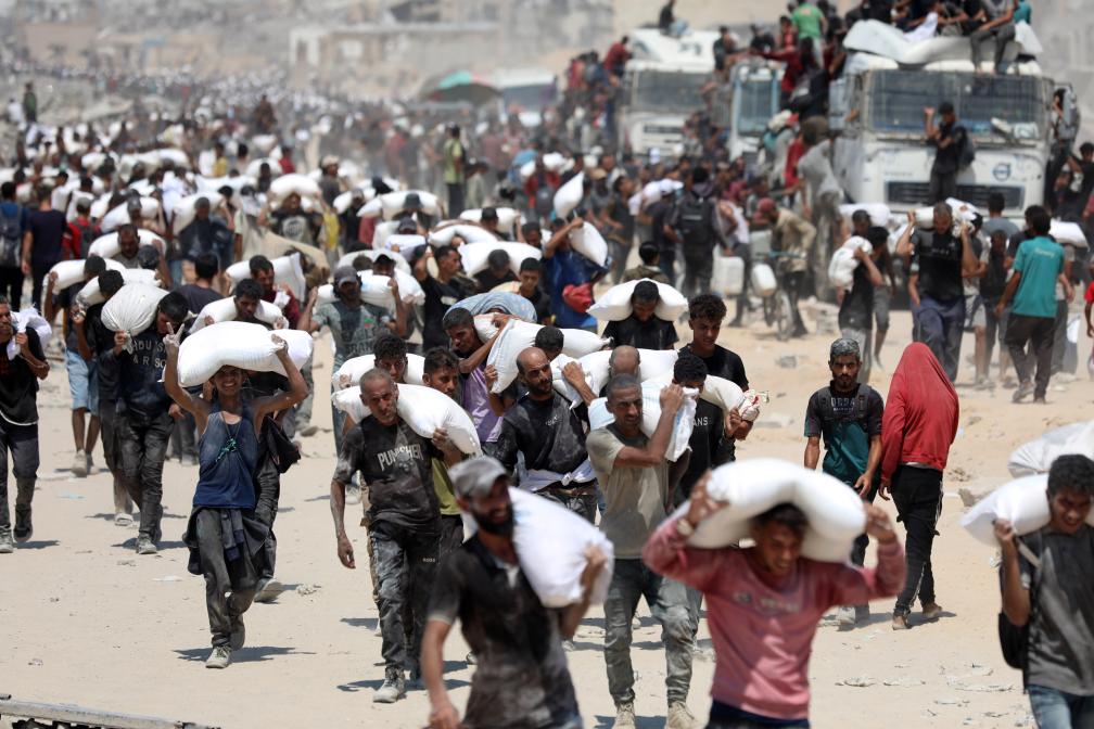 7月27日，在加沙地帶北部城鎮(zhèn)拜特拉希亞，人們領取通過邊境口岸進入加沙的援助物資。新華社發(fā)（里澤克·阿卜杜勒賈瓦德攝）