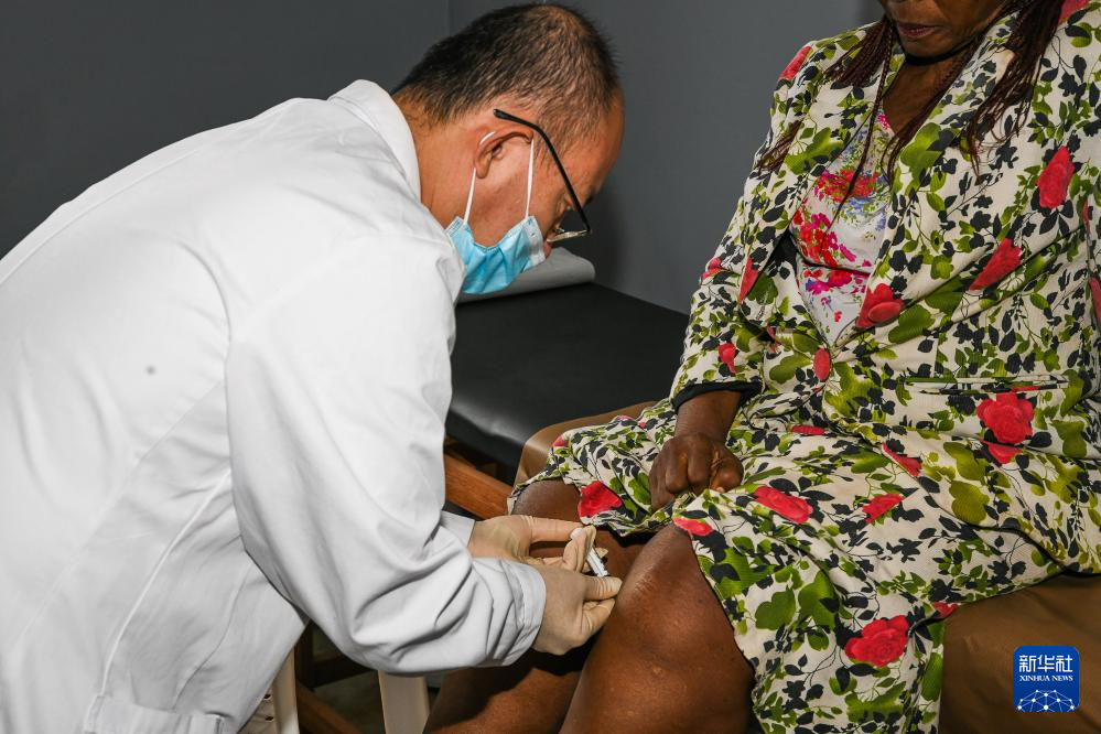 7月24日，在喀麥隆首都雅溫得郊外的阿法諾亞村，中國(guó)援喀麥隆醫(yī)療隊(duì)隊(duì)員為當(dāng)?shù)鼗颊咧委?。新華社發(fā)（科普索攝）