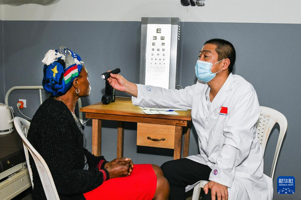7月24日，在喀麥隆首都雅溫得郊外的阿法諾亞村，中國(guó)援喀麥隆醫(yī)療隊(duì)隊(duì)員為當(dāng)?shù)鼗颊邫z查眼睛。新華社發(fā)（科普索攝）