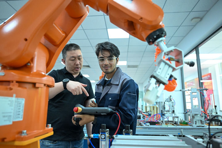 在天津現(xiàn)代職業(yè)技術(shù)學(xué)院魯班工坊實訓(xùn)教室，教師指導(dǎo)學(xué)生操作設(shè)備（2025年6月16日攝）。新華社記者 孫凡越 攝